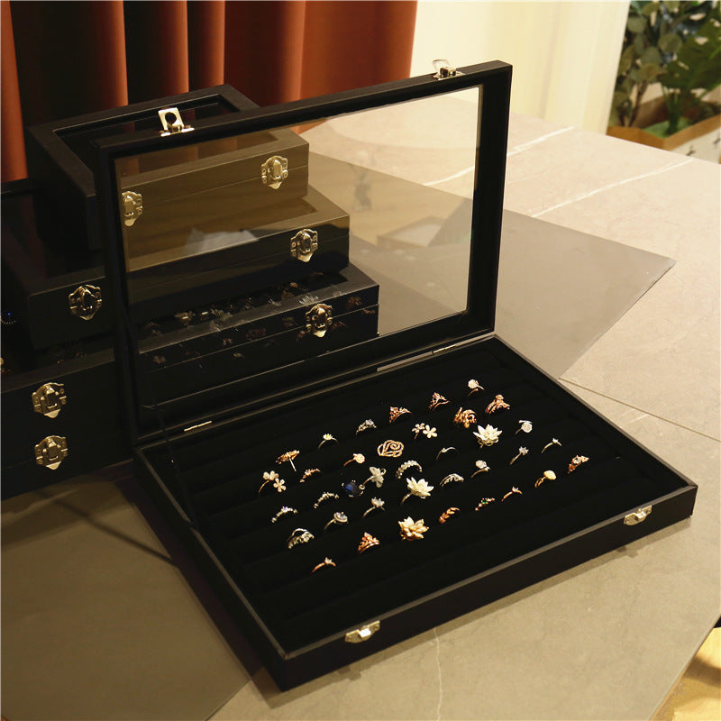 Three-quarter angle of black PU leather jewelry box with transparent glass top showing metal lock clasp and smooth edges
