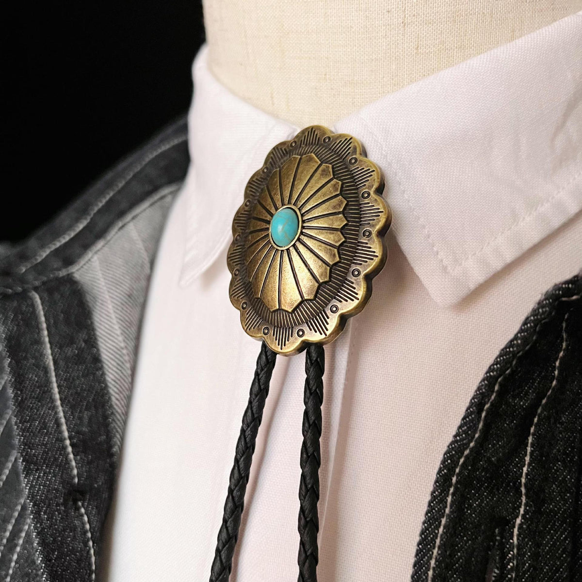 Front view of polished metal checkered antique bronze feather pendant western bolo tie with leaf pendant accent